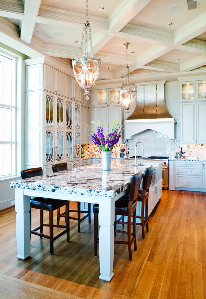 Enclosed kitchen - mid-sized traditional u-shaped medium tone wood floor enclosed kitchen idea in St Louis with a farmhouse sink, raised-panel cabinets, white cabinets, granite countertops, multicolored backsplash, stone slab backsplash, stainless steel appliances and an island