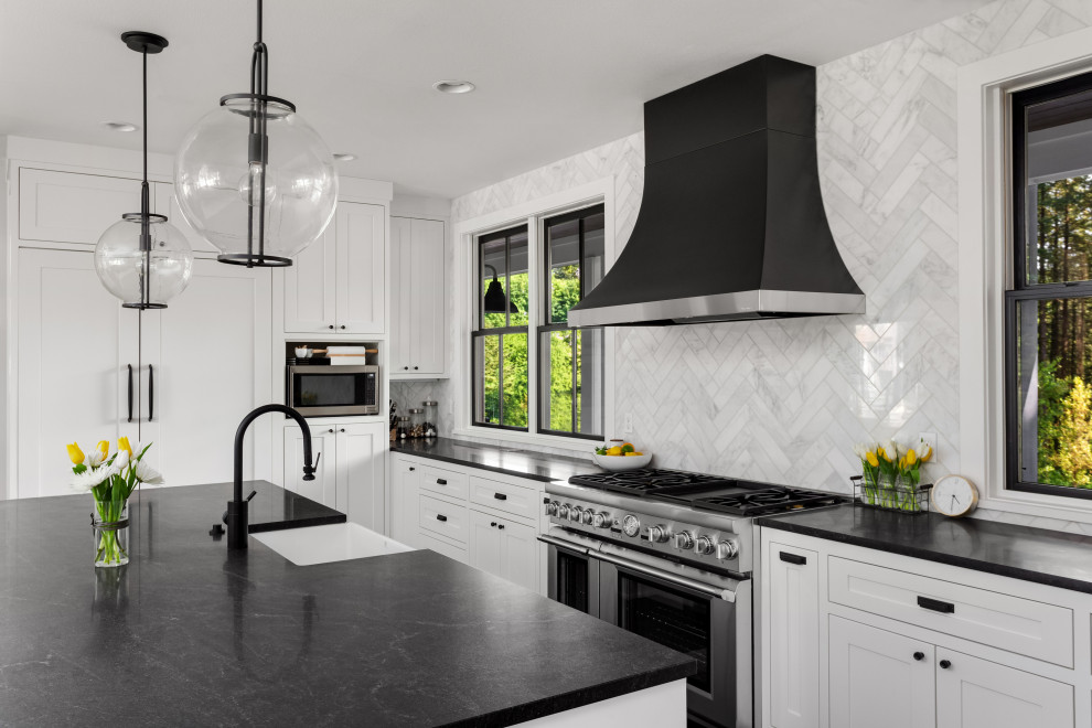 Inspiration for a huge modern dark wood floor kitchen remodel in Tampa with a farmhouse sink, shaker cabinets, white cabinets, marble countertops, white backsplash, marble backsplash, stainless steel appliances and black countertops