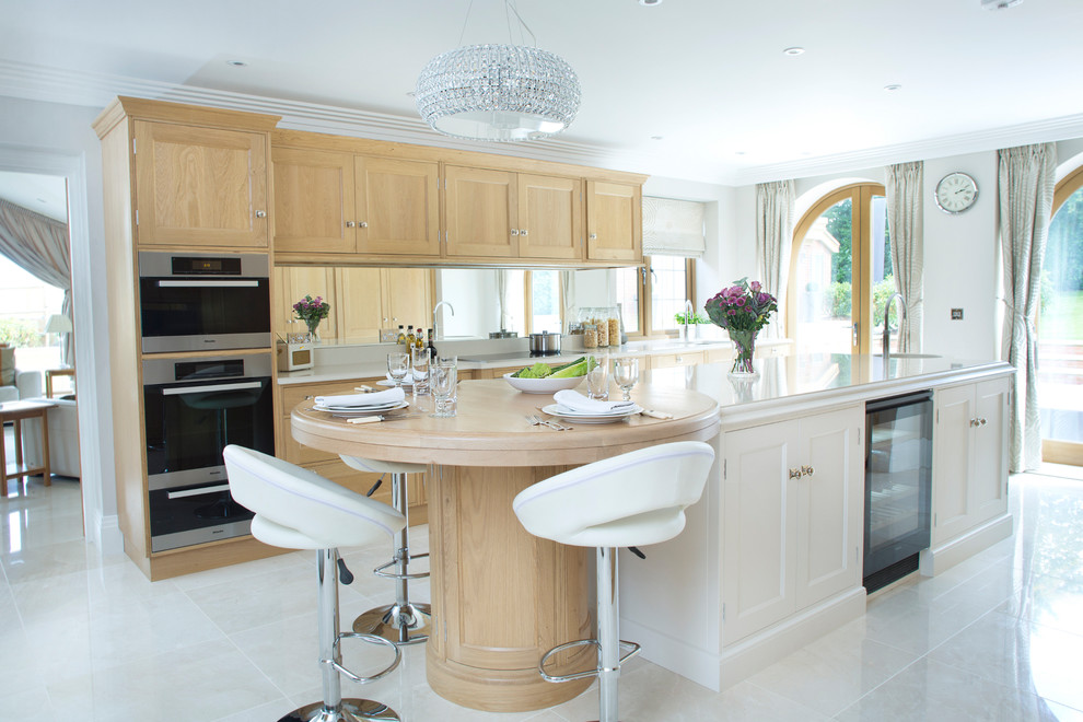 This is an example of a traditional kitchen in Kent with recessed-panel cabinets, light wood cabinets, wood worktops, mirror splashback, black appliances, an island, beige floors and beige worktops.
