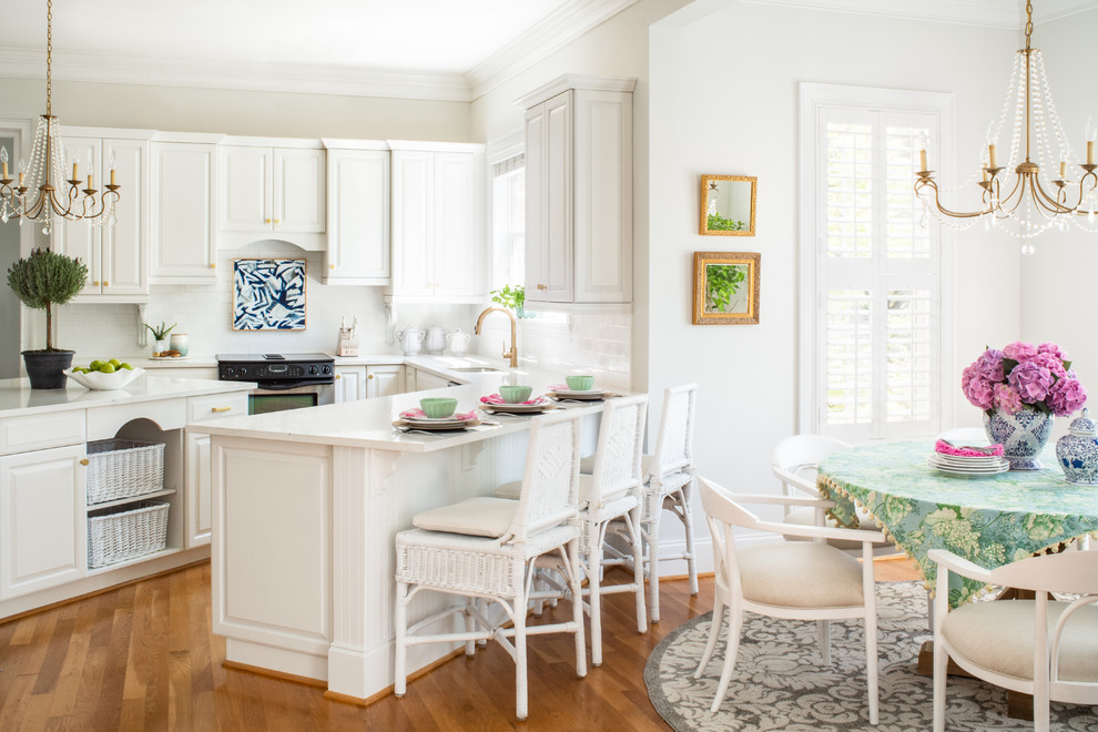 Eat-in kitchen - large traditional u-shaped medium tone wood floor eat-in kitchen idea in Other with an undermount sink, raised-panel cabinets, white cabinets, quartz countertops, white backsplash, subway tile backsplash, stainless steel appliances, an island and white countertops