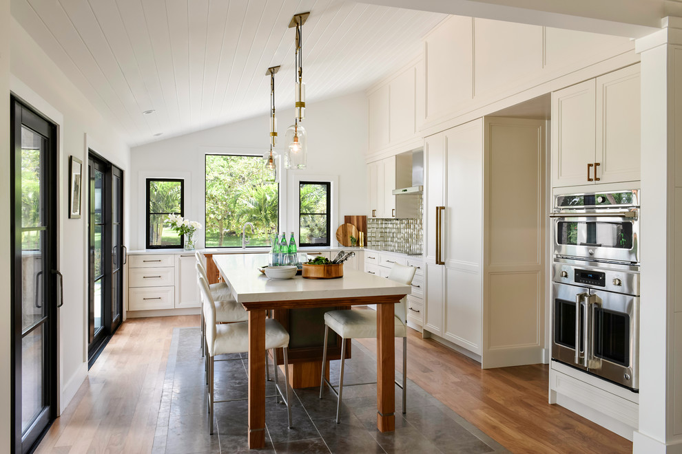 Inspiration for a large classic l-shaped open plan kitchen in Seattle with a single-bowl sink, recessed-panel cabinets, white cabinets, quartz worktops, metallic splashback, metal splashback, integrated appliances, medium hardwood flooring, an island, brown floors and white worktops.
