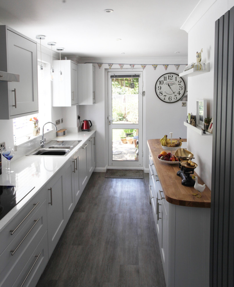 Immagine di una cucina tradizionale di medie dimensioni con lavello da incasso, ante in stile shaker, ante grigie, top in quarzite, elettrodomestici da incasso, pavimento in vinile, pavimento grigio e top bianco