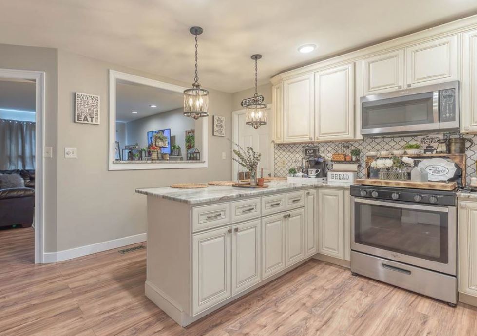 Exempel på ett stort klassiskt flerfärgad flerfärgat kök, med en undermonterad diskho, luckor med upphöjd panel, beige skåp, marmorbänkskiva, beige stänkskydd, stänkskydd i keramik, rostfria vitvaror, vinylgolv och en halv köksö