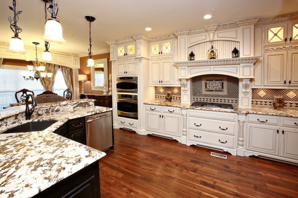 Bild på ett stort vintage vit vitt kök, med en undermonterad diskho, luckor med upphöjd panel, vita skåp, granitbänkskiva, rostfria vitvaror, mörkt trägolv, en köksö och brunt golv