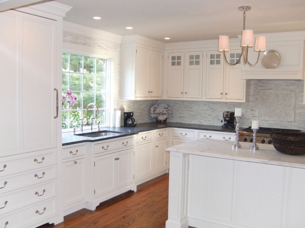 Inredning av ett klassiskt mellanstort kök, med luckor med upphöjd panel, vita skåp, bänkskiva i koppar, vitt stänkskydd, stänkskydd i stickkakel, rostfria vitvaror, ljust trägolv, en köksö och beiget golv