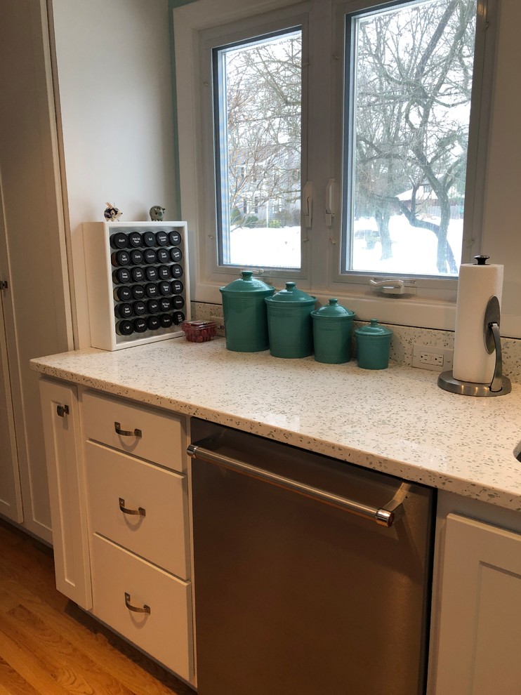 Photo of a traditional l-shaped kitchen/diner in Providence with a double-bowl sink, recycled glass countertops, green splashback, glass tiled splashback, stainless steel appliances and a breakfast bar.