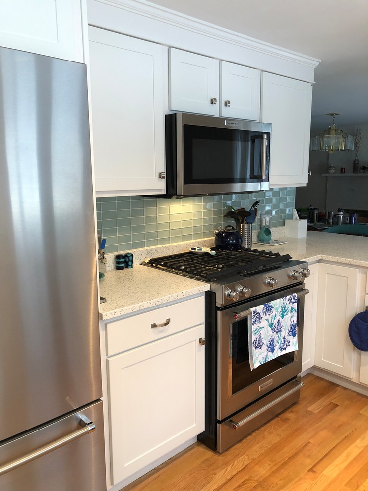 Inspiration for a traditional l-shaped kitchen/diner in Providence with a double-bowl sink, recycled glass countertops, green splashback, glass tiled splashback, stainless steel appliances and a breakfast bar.