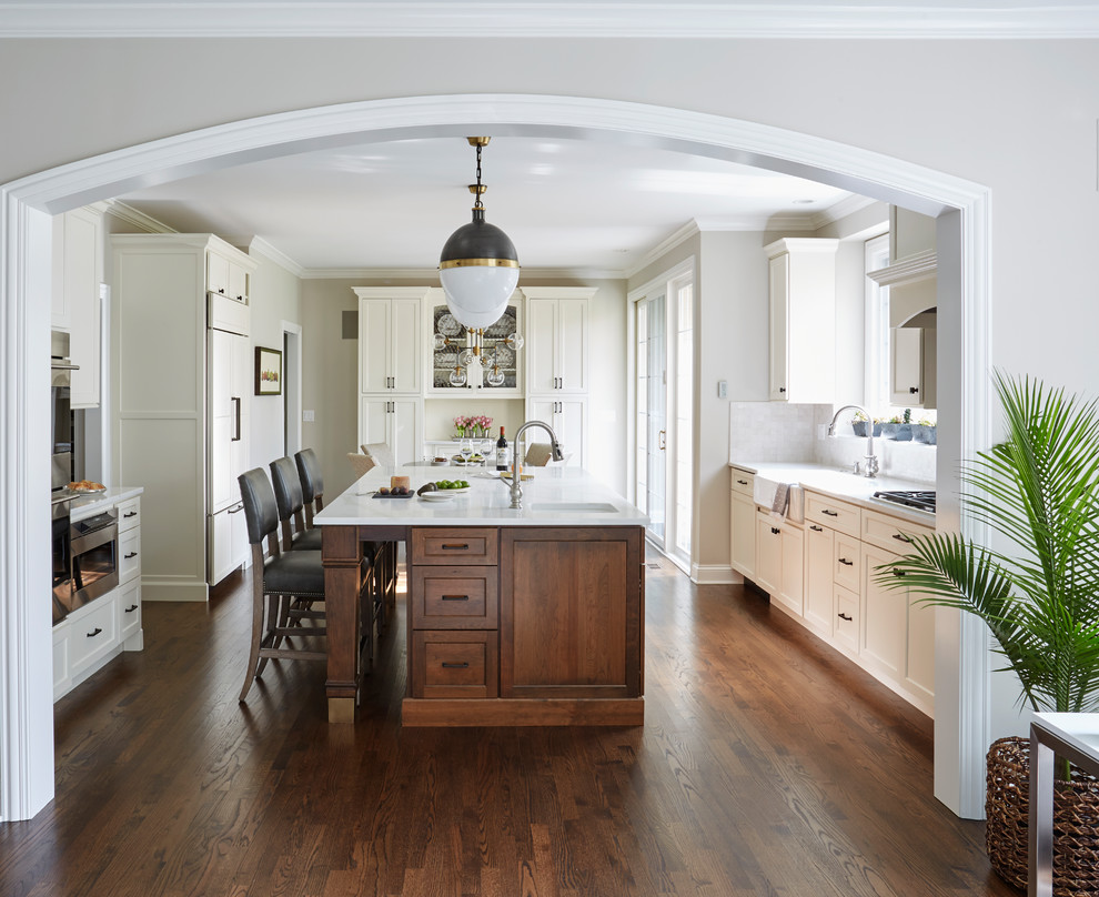 Inspiration for a large traditional open plan kitchen in San Francisco with a belfast sink, flat-panel cabinets, white cabinets, engineered stone countertops, white splashback, terracotta splashback, stainless steel appliances, medium hardwood flooring, an island and brown floors.