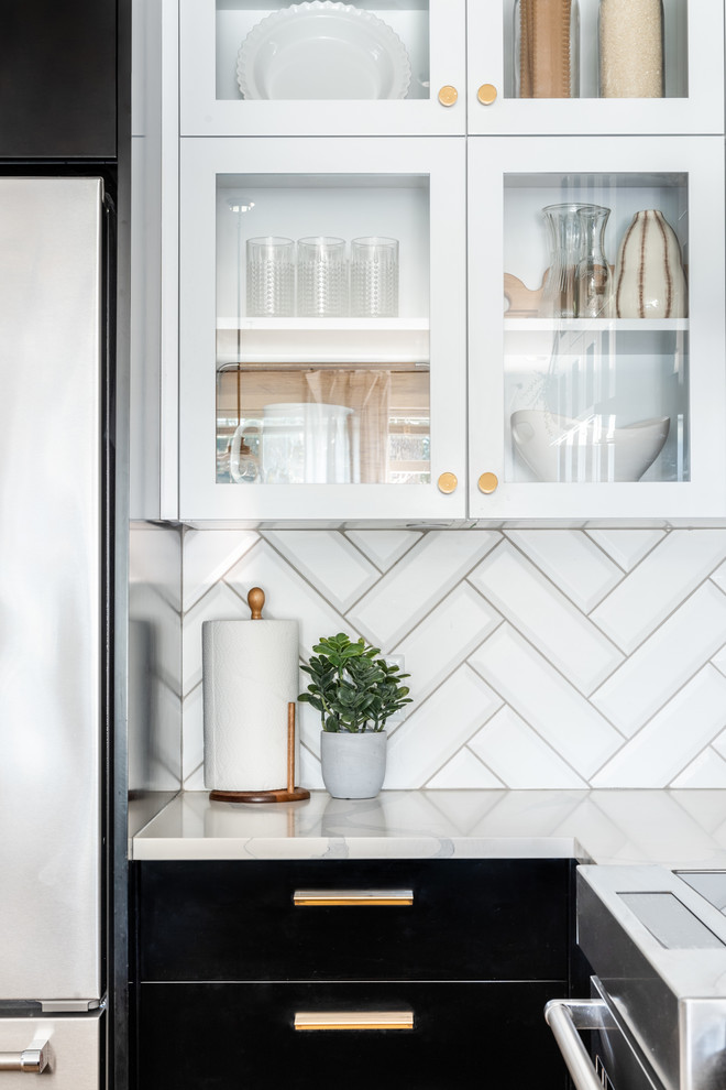 Inspiration for a small traditional u-shaped kitchen/diner in Other with a submerged sink, glass-front cabinets, black cabinets, engineered stone countertops, white splashback, porcelain splashback, stainless steel appliances, light hardwood flooring, a breakfast bar, brown floors and yellow worktops.