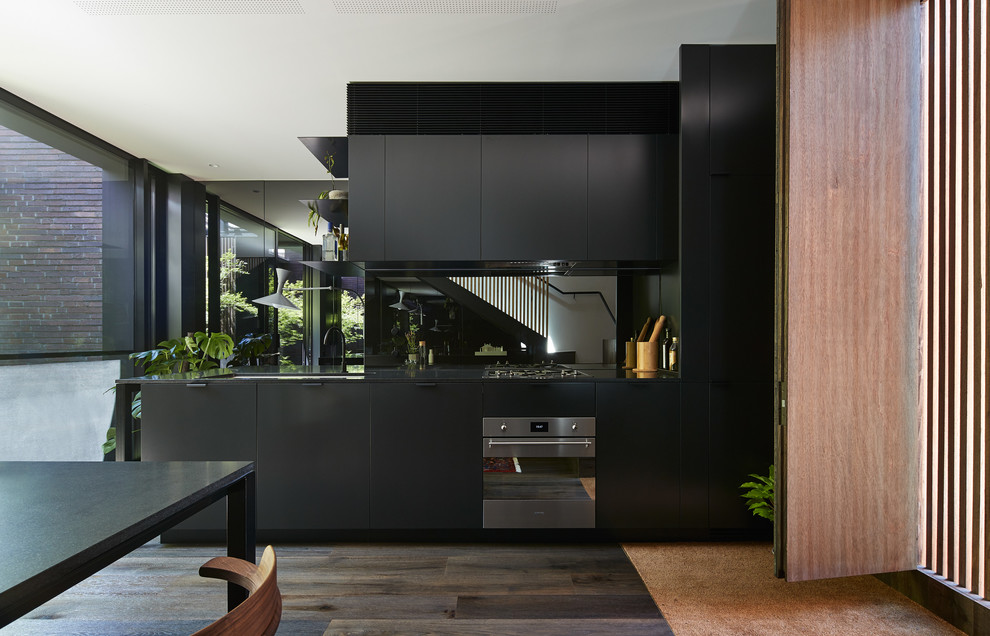 Moderne Wohnküche ohne Insel mit flächenbündigen Schrankfronten, dunklen Holzschränken, Küchengeräten aus Edelstahl und dunklem Holzboden in Melbourne