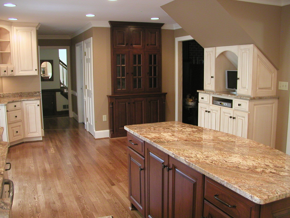 Klassisk inredning av ett mellanstort kök, med en undermonterad diskho, luckor med upphöjd panel, beige skåp, granitbänkskiva, beige stänkskydd, stänkskydd i stenkakel, rostfria vitvaror och mörkt trägolv