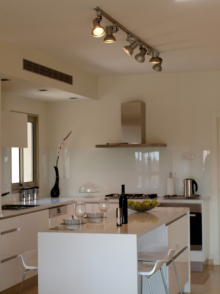 Exemple d'une cuisine moderne avec un placard à porte plane, des portes de placard blanches, une crédence blanche et une crédence en feuille de verre.