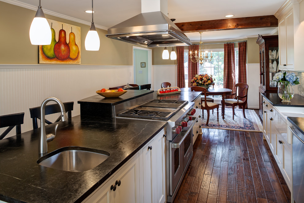 Inspiration for a small timeless galley dark wood floor eat-in kitchen remodel in Charlotte with soapstone countertops, a farmhouse sink, flat-panel cabinets, white cabinets, gray backsplash, stone tile backsplash, stainless steel appliances and an island