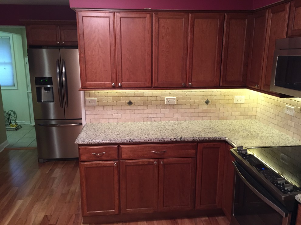 This is an example of a small classic l-shaped kitchen/diner in Chicago with a double-bowl sink, recessed-panel cabinets, medium wood cabinets, laminate countertops, beige splashback, metro tiled splashback, white appliances and medium hardwood flooring.