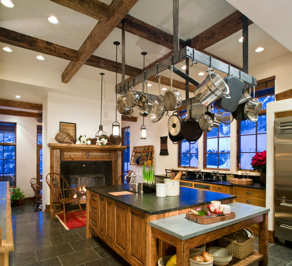 Inspiration for a rustic kitchen remodel in Other with a double-bowl sink, raised-panel cabinets, medium tone wood cabinets, soapstone countertops, stainless steel appliances and an island