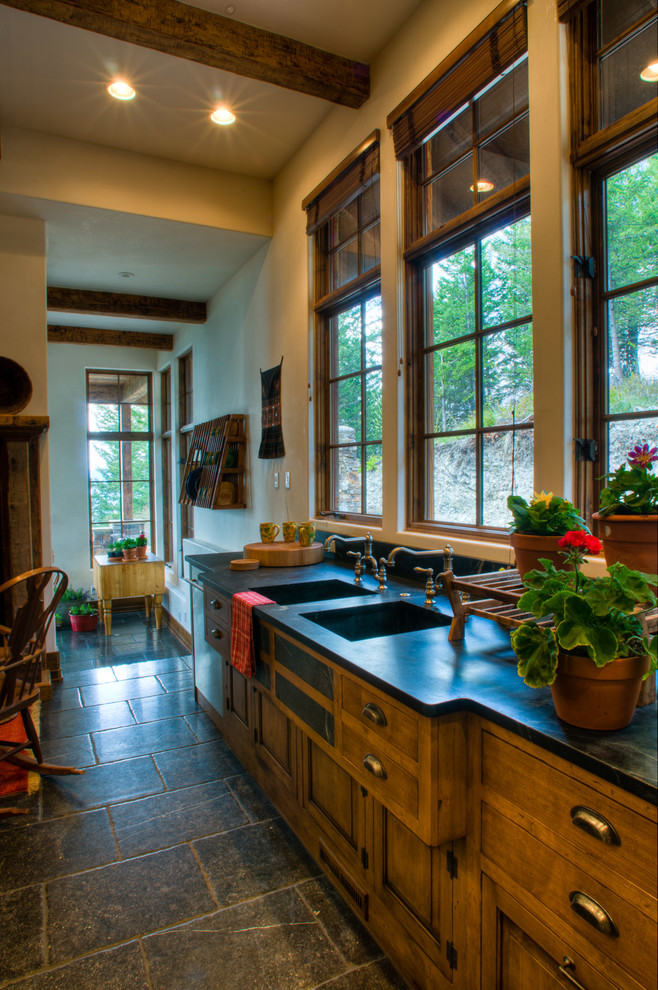 This is an example of a rustic kitchen in Other with a double-bowl sink, raised-panel cabinets, medium wood cabinets, soapstone worktops, stainless steel appliances and an island.