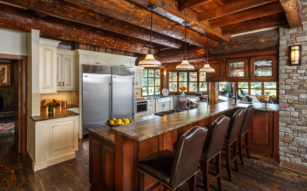Photo of a rustic u-shaped kitchen in Albuquerque with raised-panel cabinets, beige cabinets, a breakfast bar, a submerged sink, stainless steel appliances and dark hardwood flooring.