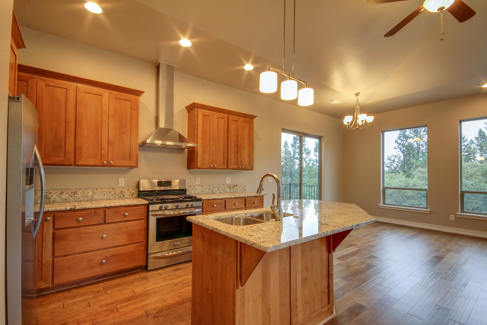 This is an example of a medium sized traditional l-shaped kitchen in Other with a double-bowl sink, shaker cabinets, medium wood cabinets, granite worktops, stainless steel appliances, medium hardwood flooring, an island and brown floors.