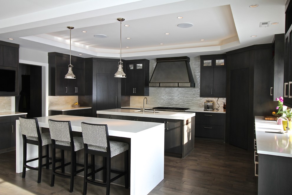 Design ideas for a large contemporary u-shaped open plan kitchen in Omaha with multiple islands, a submerged sink, flat-panel cabinets, dark wood cabinets, engineered stone countertops, metallic splashback, matchstick tiled splashback, integrated appliances, dark hardwood flooring and brown floors.