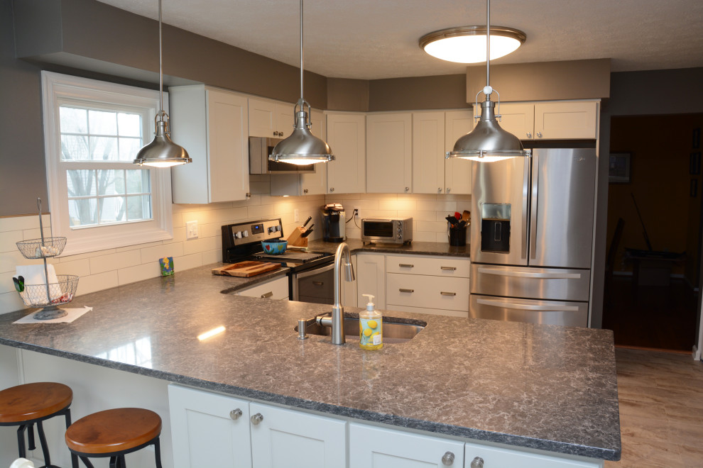Medium sized classic u-shaped kitchen/diner in Baltimore with a submerged sink, recessed-panel cabinets, white cabinets, engineered stone countertops, white splashback, stainless steel appliances, a breakfast bar, beige floors and grey worktops.