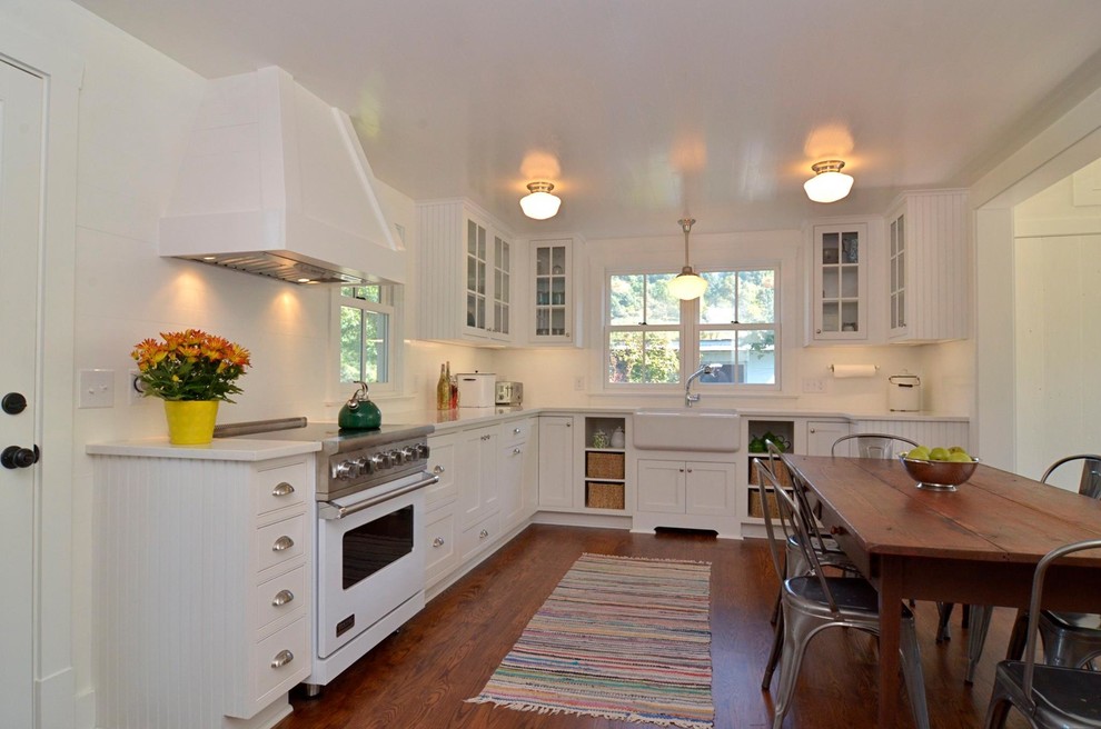 Inspiration for a small farmhouse u-shaped medium tone wood floor eat-in kitchen remodel in Other with a farmhouse sink, beaded inset cabinets, white cabinets, quartz countertops, white backsplash, white appliances and no island