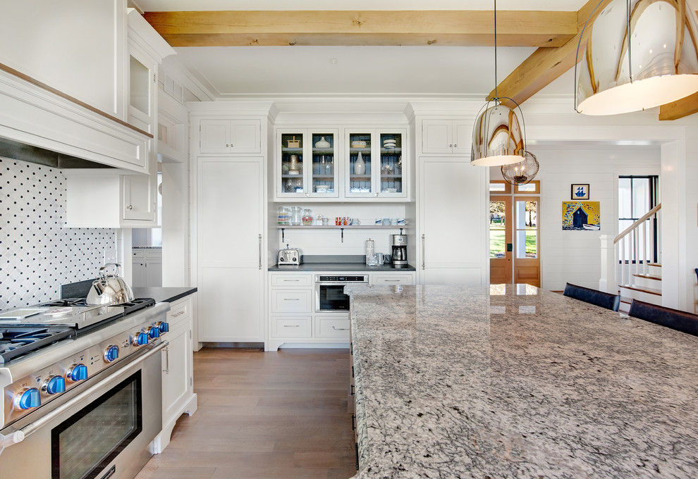Bild på ett stort lantligt u-kök, med skåp i shakerstil, vita skåp, stänkskydd i mosaik, integrerade vitvaror, en köksö, brunt golv, mellanmörkt trägolv, en rustik diskho och granitbänkskiva