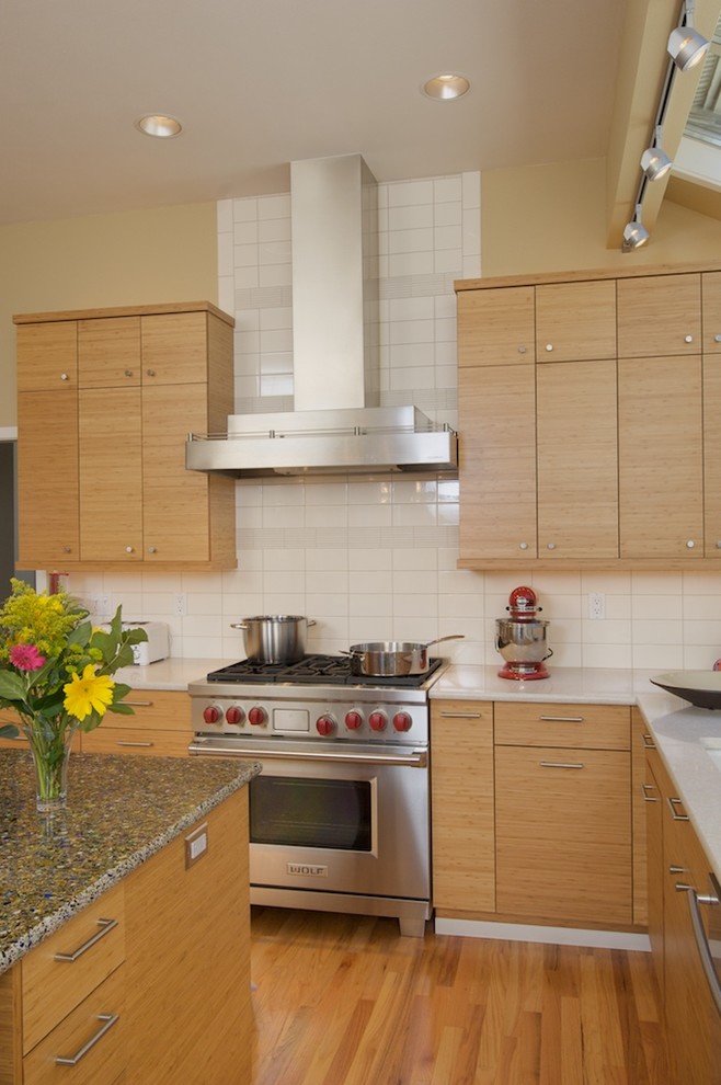 Immagine di una cucina design con ante lisce, ante in legno chiaro, paraspruzzi bianco, paraspruzzi con piastrelle diamantate, elettrodomestici in acciaio inossidabile e top in vetro riciclato