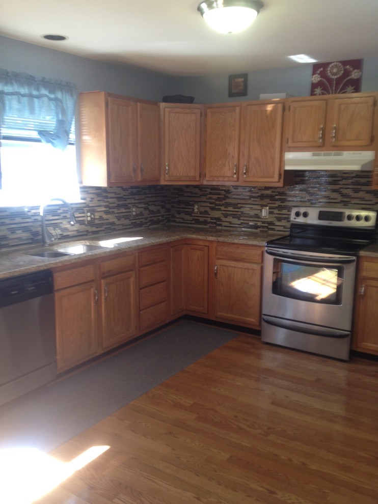 Foto på ett mellanstort medelhavsstil kök, med en dubbel diskho, skåp i ljust trä, granitbänkskiva, flerfärgad stänkskydd, stänkskydd i glaskakel, svarta vitvaror och ljust trägolv