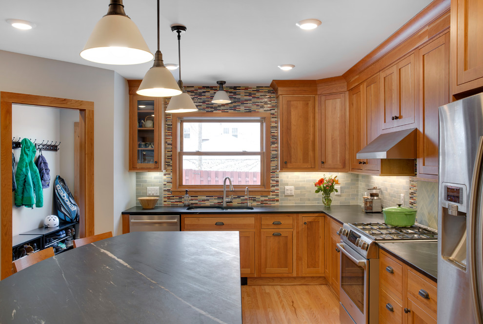 Inspiration for a large craftsman l-shaped light wood floor enclosed kitchen remodel in Minneapolis with an undermount sink, shaker cabinets, light wood cabinets, soapstone countertops, gray backsplash, ceramic backsplash, stainless steel appliances and an island