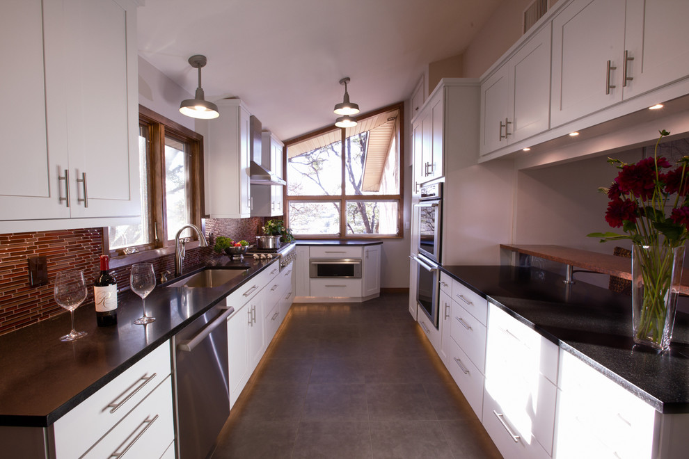 Modern inredning av ett kök, med en enkel diskho, skåp i shakerstil, gula skåp, granitbänkskiva, rött stänkskydd och rostfria vitvaror
