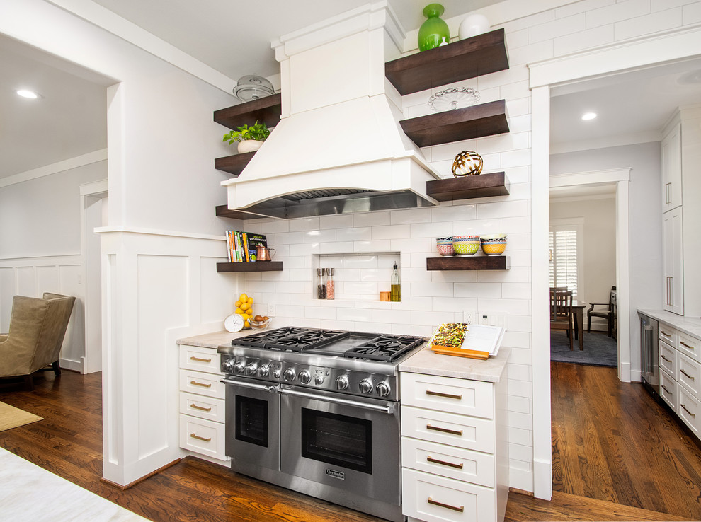 ダラスにある高級な広いトランジショナルスタイルのおしゃれなキッチン (ドロップインシンク、フラットパネル扉のキャビネット、白いキャビネット、珪岩カウンター、白いキッチンパネル、セラミックタイルのキッチンパネル、シルバーの調理設備、濃色無垢フローリング、茶色い床、グレーのキッチンカウンター) の写真