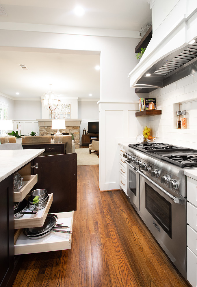 ダラスにある高級な広いトランジショナルスタイルのおしゃれなキッチン (ドロップインシンク、フラットパネル扉のキャビネット、白いキャビネット、珪岩カウンター、白いキッチンパネル、セラミックタイルのキッチンパネル、シルバーの調理設備、濃色無垢フローリング、茶色い床、グレーのキッチンカウンター) の写真