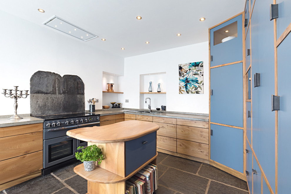 На фото: кухня среднего размера в стиле неоклассика (современная классика) с двойной мойкой, плоскими фасадами, столешницей из бетона, островом, серым полом, серой столешницей, синими фасадами и черным фартуком с