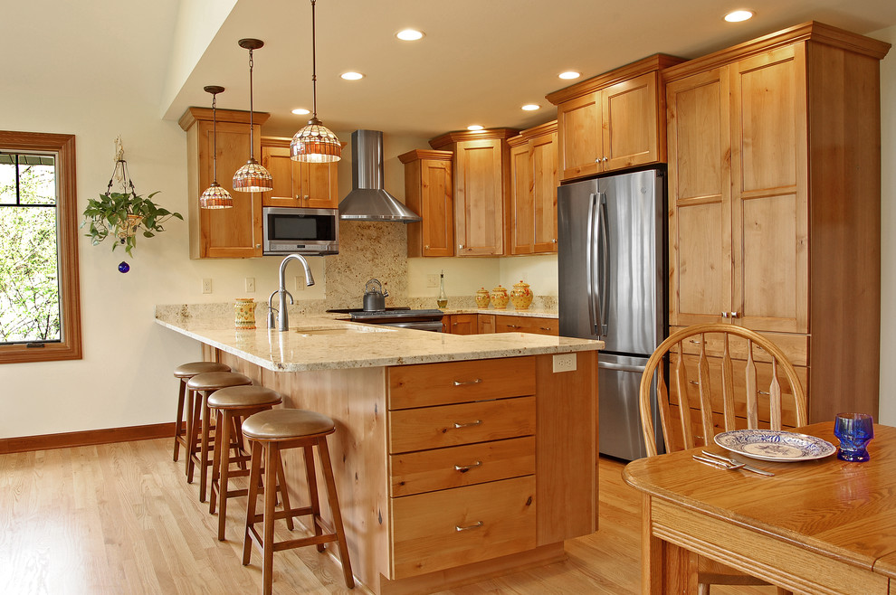 Klassische Küche mit Unterbauwaschbecken, Granit-Arbeitsplatte, Küchengeräten aus Edelstahl und hellem Holzboden in Milwaukee