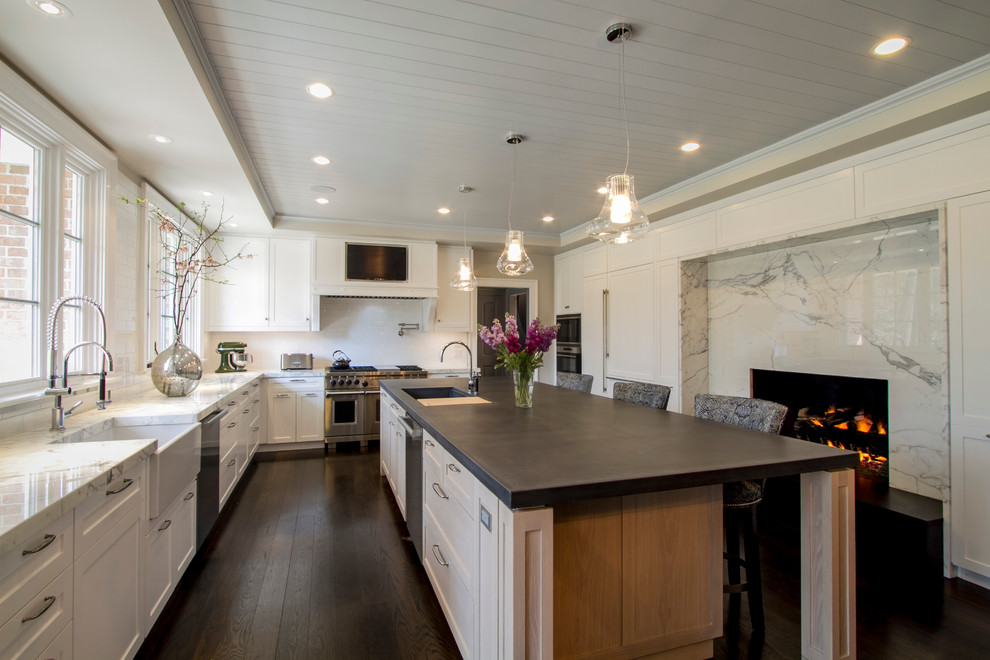 Example of a large transitional l-shaped dark wood floor kitchen design in New York with a farmhouse sink, shaker cabinets, white cabinets, concrete countertops, white backsplash, ceramic backsplash, stainless steel appliances and an island
