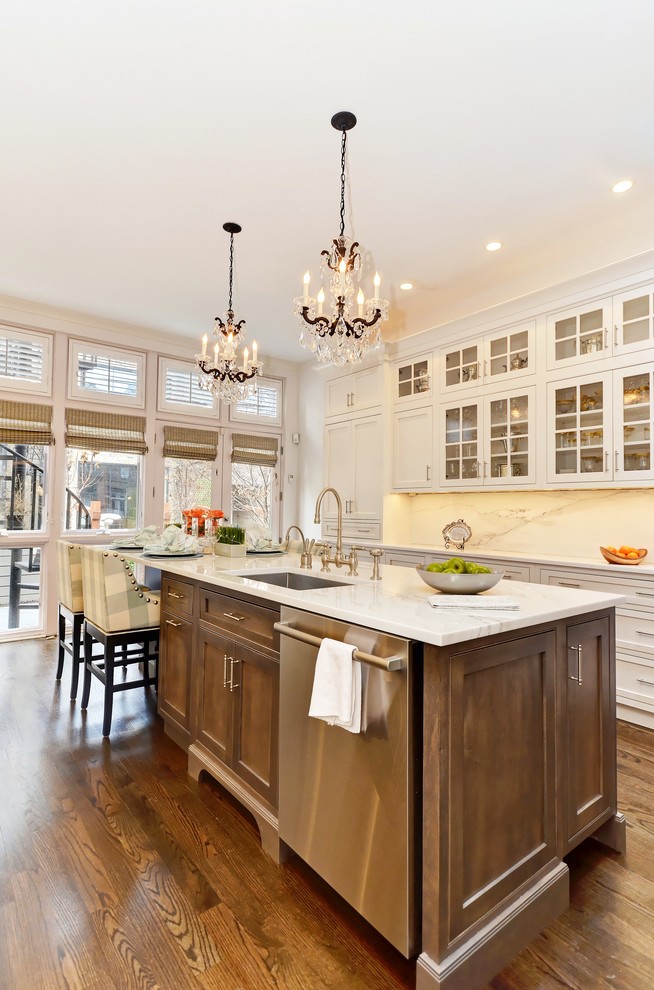 Inspiration for a traditional kitchen in Chicago with a submerged sink, shaker cabinets, white cabinets, white splashback, integrated appliances, dark hardwood flooring, an island and brown floors.
