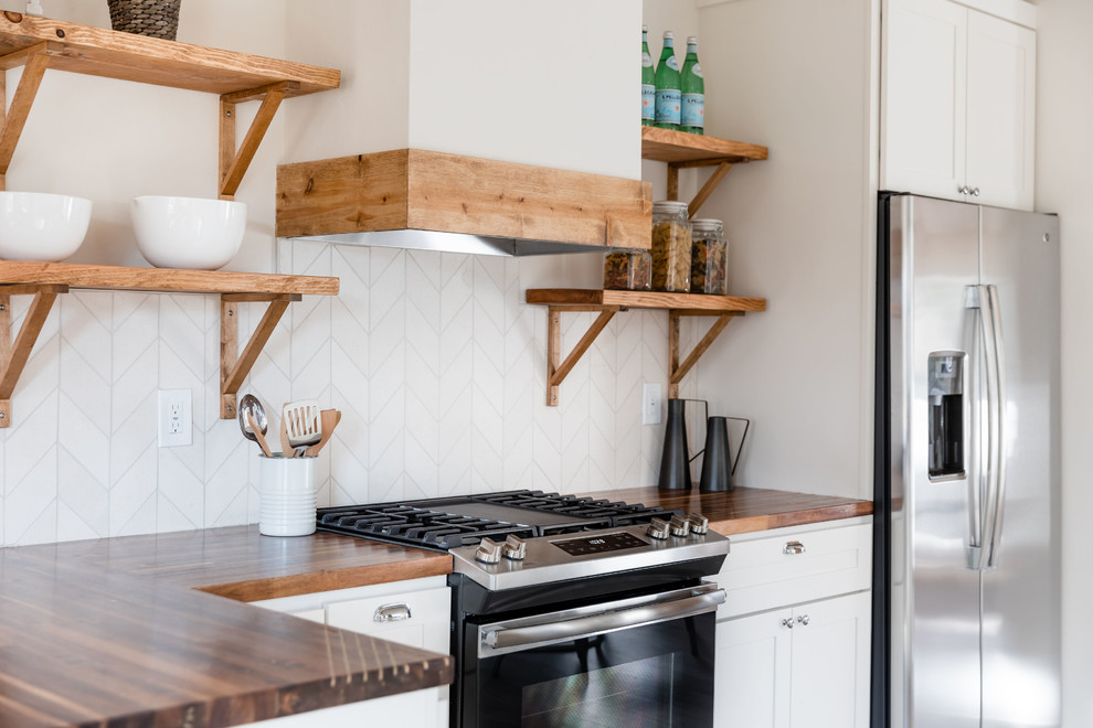 Idee per una piccola cucina country con lavello stile country, ante in stile shaker, ante bianche, top in legno, paraspruzzi beige, paraspruzzi con piastrelle in pietra, elettrodomestici in acciaio inossidabile, pavimento in laminato, penisola e pavimento grigio