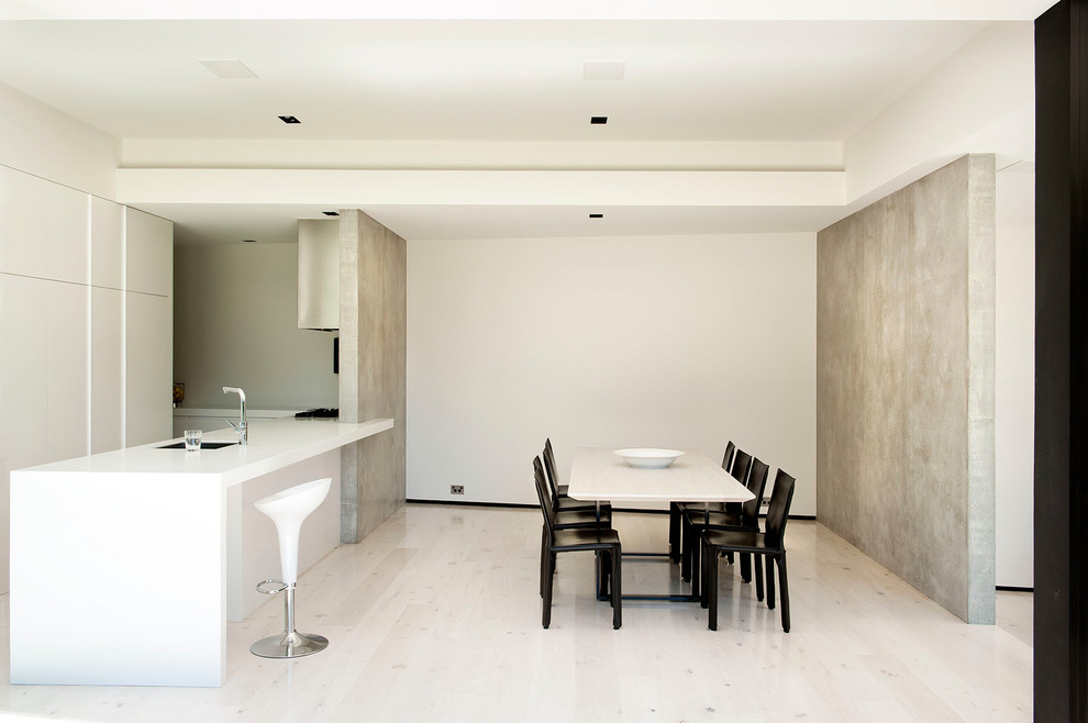 Cette image montre une cuisine américaine parallèle et encastrable minimaliste avec un évier 1 bac, un placard à porte plane et des portes de placard blanches.