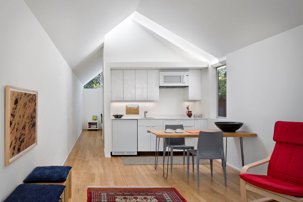 Einzeilige, Kleine, Offene Moderne Küche mit Unterbauwaschbecken, flächenbündigen Schrankfronten, weißen Schränken und braunem Holzboden in San Francisco