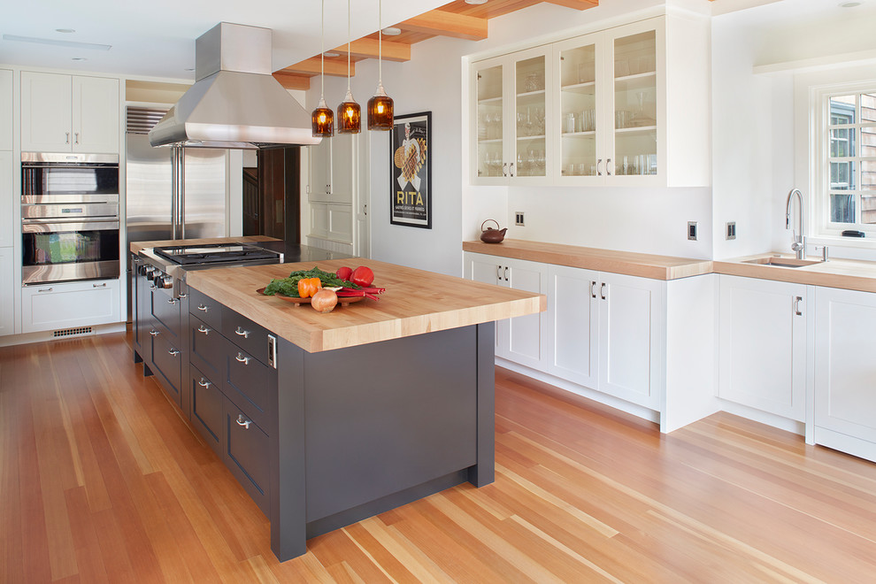 Inspiration for a transitional u-shaped medium tone wood floor and brown floor kitchen remodel in San Francisco with an undermount sink, shaker cabinets, gray cabinets, wood countertops, stainless steel appliances and an island