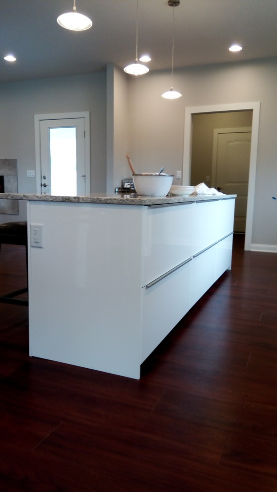 Exempel på ett modernt kök, med en undermonterad diskho, släta luckor, vita skåp, bänkskiva i kvarts, vitt stänkskydd, rostfria vitvaror och en köksö