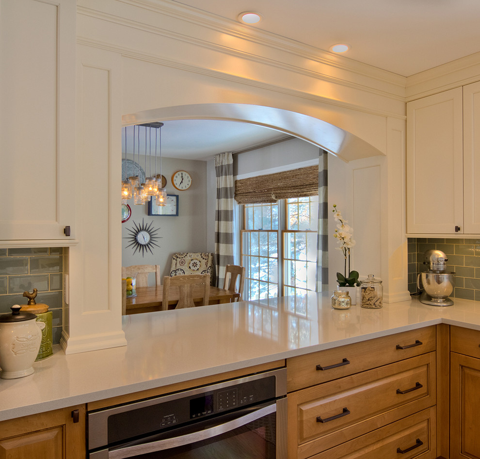 Mid-sized transitional l-shaped medium tone wood floor eat-in kitchen photo in Detroit with an undermount sink, recessed-panel cabinets, light wood cabinets, solid surface countertops, blue backsplash, glass tile backsplash, stainless steel appliances and an island