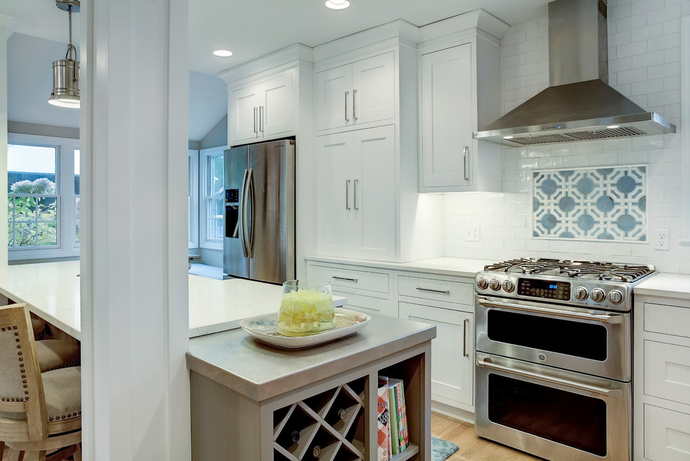 Mid-sized transitional galley light wood floor eat-in kitchen photo in Grand Rapids with a farmhouse sink, shaker cabinets, white cabinets, quartz countertops, white backsplash, ceramic backsplash, stainless steel appliances and an island