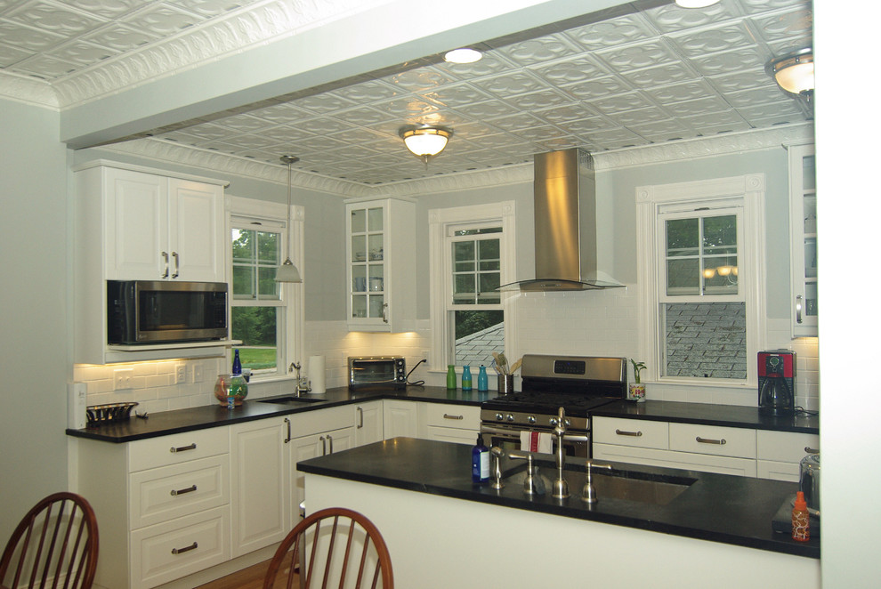 Idéer för att renovera ett mellanstort vintage kök, med en undermonterad diskho, luckor med upphöjd panel, vita skåp, bänkskiva i täljsten, vitt stänkskydd, stänkskydd i tunnelbanekakel, rostfria vitvaror, ljust trägolv och en halv köksö