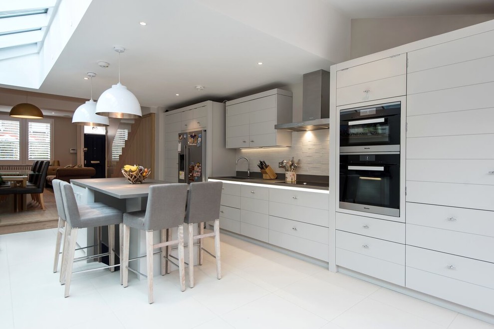 Inspiration for a medium sized contemporary single-wall open plan kitchen in London with flat-panel cabinets, grey cabinets, white splashback, brick splashback and white floors.