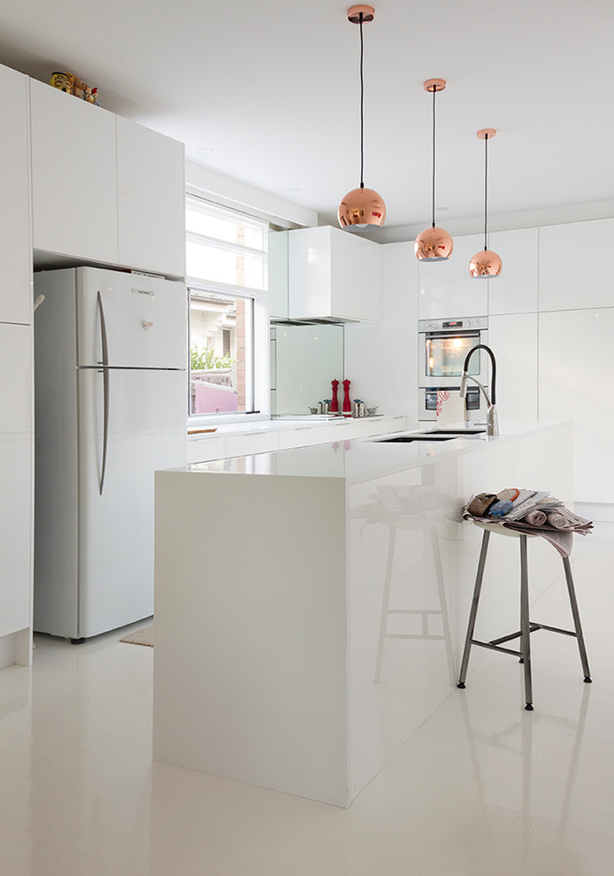 Immagine di una cucina design con lavello sottopiano, ante lisce, ante bianche, elettrodomestici in acciaio inossidabile, paraspruzzi a specchio e pavimento in gres porcellanato