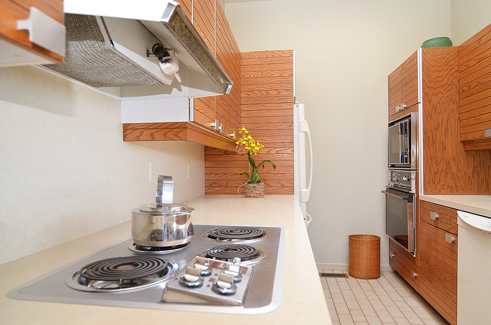 シアトルにあるお手頃価格の中くらいなミッドセンチュリースタイルのおしゃれなキッチン (中間色木目調キャビネット、ラミネートカウンター、白い調理設備、セラミックタイルの床、フラットパネル扉のキャビネット) の写真