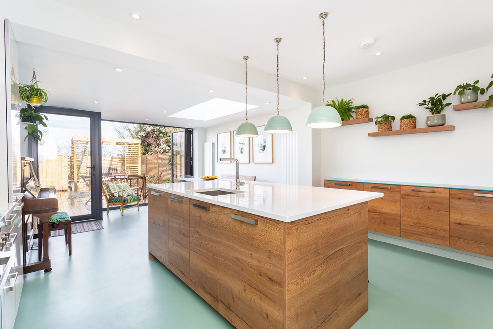 This is an example of a contemporary galley kitchen in London with a submerged sink, flat-panel cabinets, medium wood cabinets, an island, green floors and white worktops.