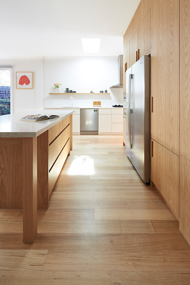 Inspiration for a large nautical single-wall open plan kitchen in Melbourne with a double-bowl sink, beaded cabinets, medium wood cabinets, marble worktops, stainless steel appliances, light hardwood flooring, an island, brown floors and white worktops.