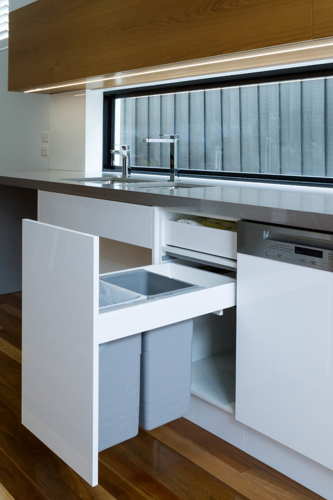 Esempio di una grande cucina moderna con lavello sottopiano, ante lisce, top in quarzo composito, pavimento in legno massello medio e nessuna isola